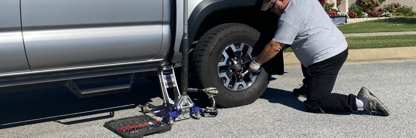 Northwest Arkansas -- Razor Roadside assistance technician with jack and necessary tools responds to a tire-change call on a truck.